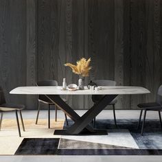 a dining table with two chairs and a vase on the top, in front of a wood paneled wall