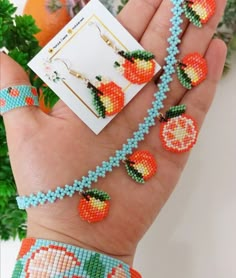 the beaded bracelets are being held in someone's hand with fruit on them