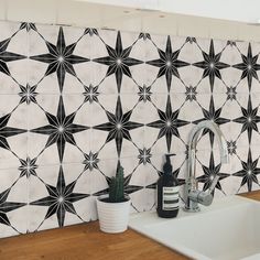 a kitchen sink with a black and white tile design on the back wall behind it