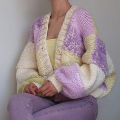 a woman sitting on the floor wearing a purple and white sweater