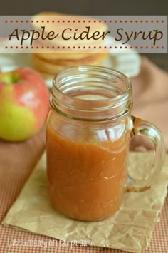 an apple cider syrup in a mason jar on a table with apples and napkins