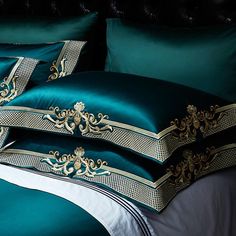 a close up of a bed with green sheets and pillows on top of each other