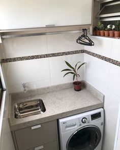 a washer and dryer in a small room with white tiles on the walls