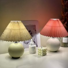 two lamps sitting on top of a white table next to a framed photo and an electronic device