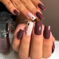 a woman with brown and white nail polishes on her nails next to a bottle of lipstick