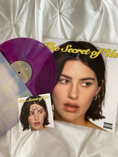 a purple vinyl record with an ad for the secret club next to it on a white sheet