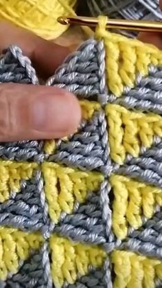 someone is crocheting on the side of a yellow and gray granny blanket with yarn