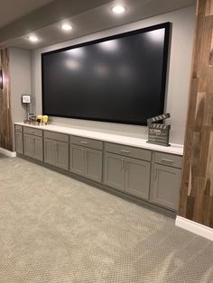 a large screen mounted to the side of a wall in a room with carpeted flooring