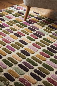 an area rug with multicolored circles on it in front of a chair and footstool