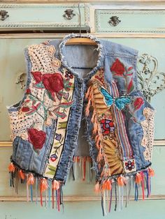 an old jean vest with embroidered flowers and hearts is hanging on a door knobs