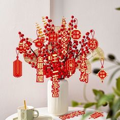 a vase filled with red flowers on top of a table next to a cup and saucer