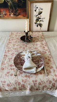 a table topped with a plate covered in white cloth next to a painting and candle