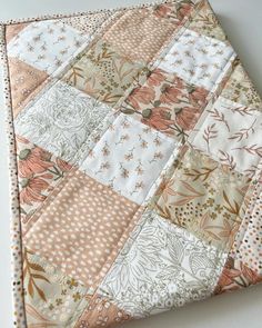 an orange and white patchwork quilt on top of a table