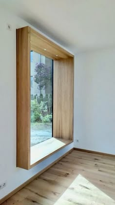 an empty room with wooden floors and a large window in the corner that is partially open