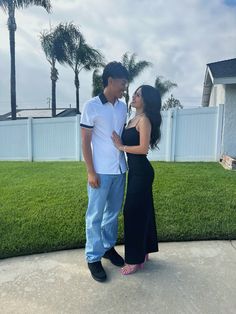 a man and woman standing next to each other in front of a white picket fence