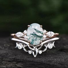 a ring with a green stone surrounded by white diamonds on top of a piece of wood