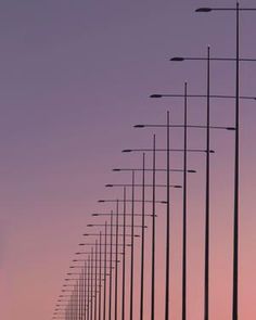 a row of street lights sitting next to each other on top of a road under a purple sky