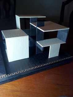 three black and white shelves sitting on top of a wooden table