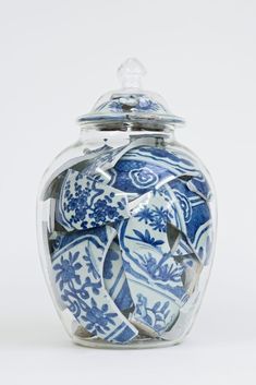 a blue and white glass jar with an ornate design on the lid is shown in front of a white background