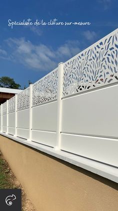 the side of a building with a white fence and blue sky in the back ground