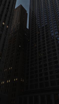 two tall buildings are lit up in the night sky, with no one around them