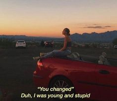 a woman sitting on top of a red car