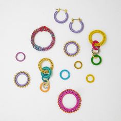 several pairs of colorful beaded hoop earrings on a white surface with one earring in the middle