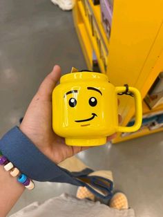 a person holding a yellow mug with a face on it