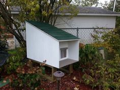 a white bird house with a green roof