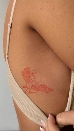 a woman's stomach with a tattoo on the side of her body and an orange bird