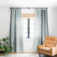 a living room with a chair, window and potted plant on the floor in front of it