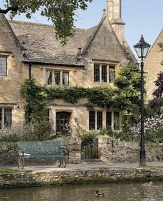 an old stone house next to a river with ducks swimming in the water near it