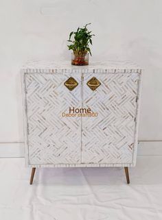 a white cabinet with plants on top and the words home decor written in gold lettering