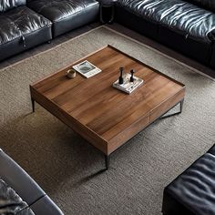 a living room with black leather couches and a wooden coffee table in the middle