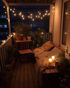 a porch with lights strung over it and some plants on the balcony table next to the couch