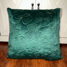 a green velvet pillow sitting on top of a wooden floor