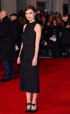 a woman standing on top of a red carpet in front of a group of people