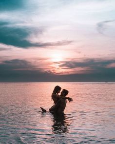 two people in the water at sunset, one is holding the other's head