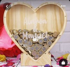 a wooden heart shaped box filled with coins and the word marriage on it's side