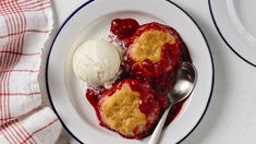 a white plate topped with ice cream and strawberry cobbler next to a red checkered napkin