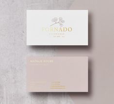 two business cards sitting on top of each other with gold foil lettering and a white background