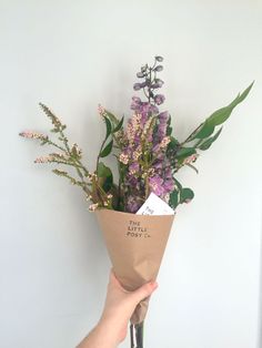 a hand holding a paper bag with flowers in it