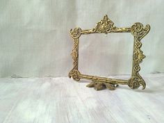 an ornate gold frame sitting on top of a white table next to a stuffed animal