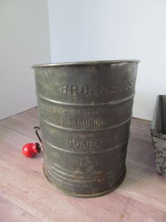 a large metal bucket sitting on top of a wooden table next to a red apple