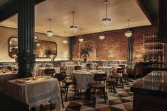 an empty restaurant with tables and chairs set up for formal dining in front of a brick wall