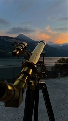 a telescope sitting on top of a wooden tripod next to a body of water