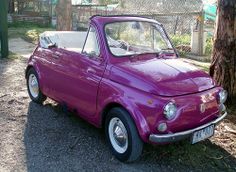 an old purple car parked next to a tree