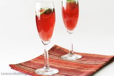 two wine glasses filled with red liquid and garnished with green leafy strawberries