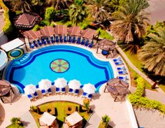 an aerial view of a resort pool with lounge chairs and umbrellas around the pool