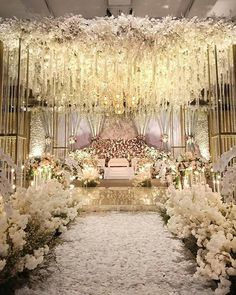 an aisle decorated with white flowers and chandeliers